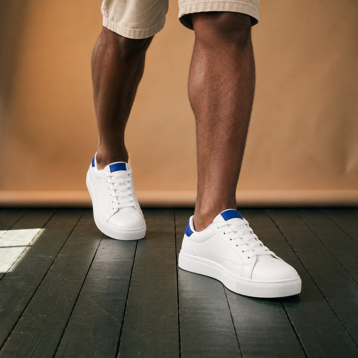 Baskets blanches en cuir style rétro années 80 portées en studio avec un jean, vue de face Bild
