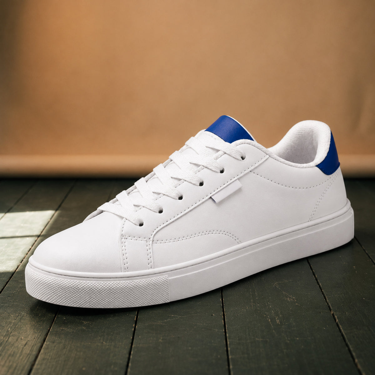 Gros plan sur le cuir blanc, la semelle en caoutchouc et le détail coloré au talon des baskets rétro années 80 Bild