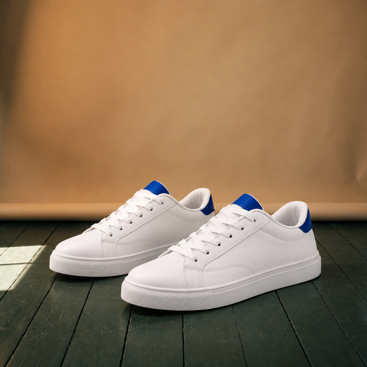 Paire de baskets blanches en cuir style rétro années 80 posée sur fond neutre, talon bleu visible Bild