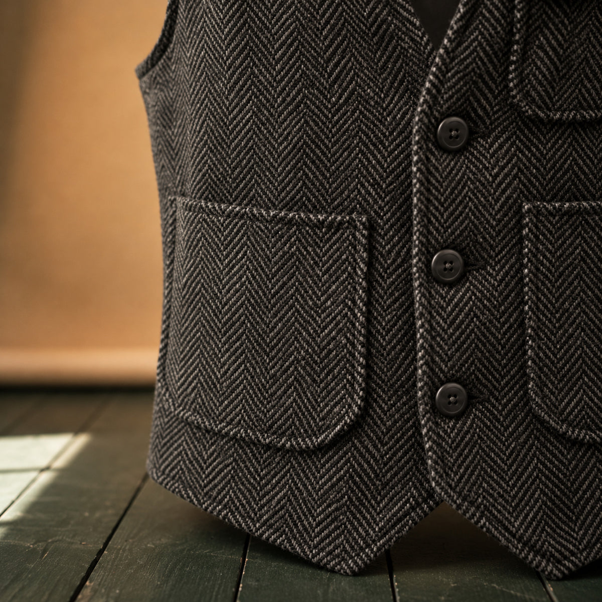 Gros plan sur la laine à chevrons, les poches plaquées et les boutons du gilet homme vintage Bild