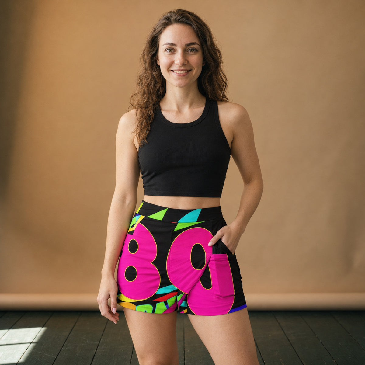 Jupe culotte année 80 à imprimé néon portée en studio avec un body noir, vue de face Bild