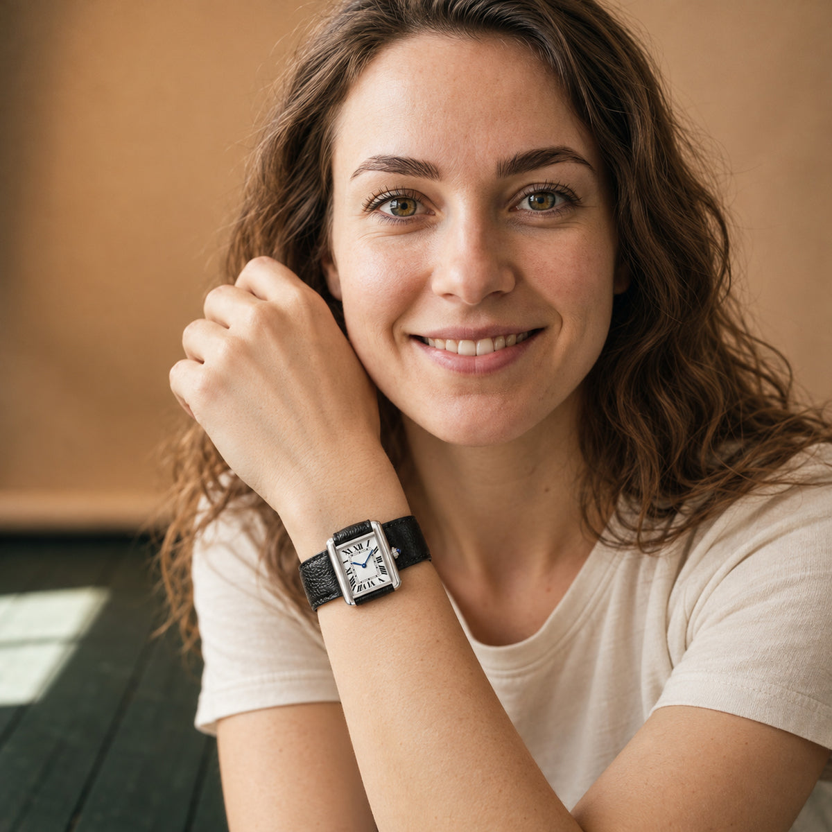 Montre rectangulaire femme à cadran blanc et chiffres romains portée au poignet, bracelet noir grainé, vue en studio Bild
