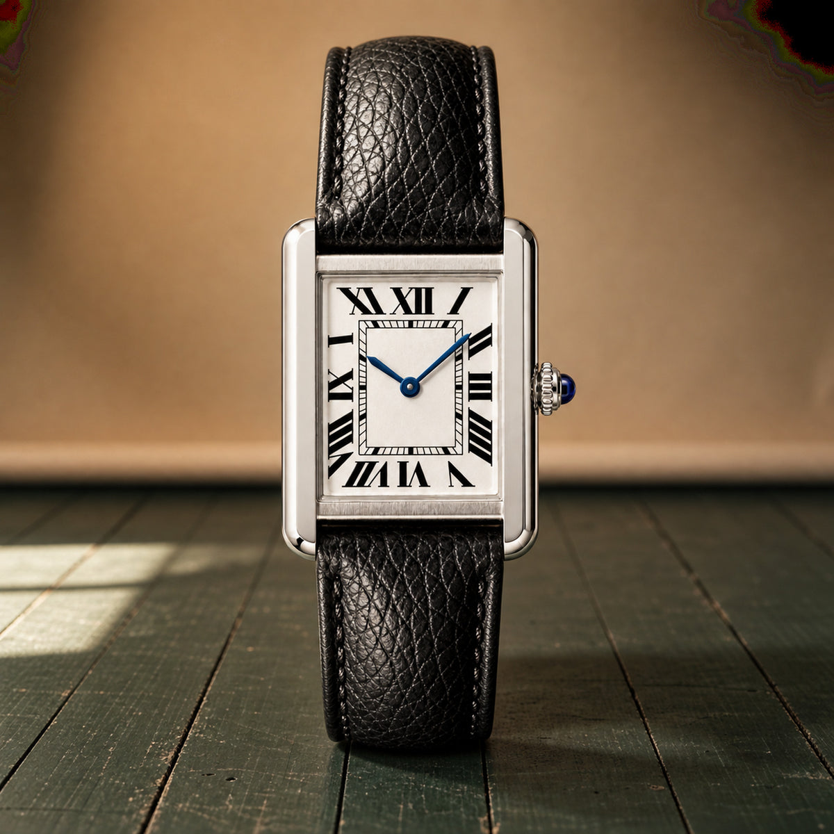 Gros plan sur le cadran blanc à chiffres romains, les aiguilles bleues et le cabochon de la montre rectangulaire femme Bild