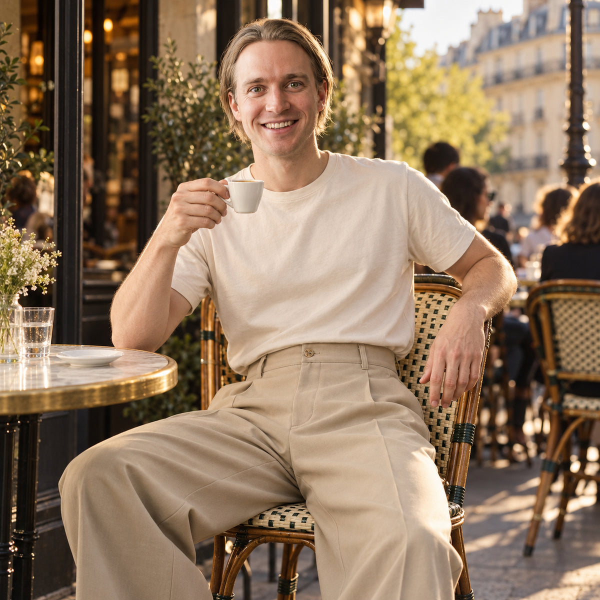 Homme en pantalon vintage à pinces taille haute assis à une terrasse de café parisienne, fin d'après-midi Bild