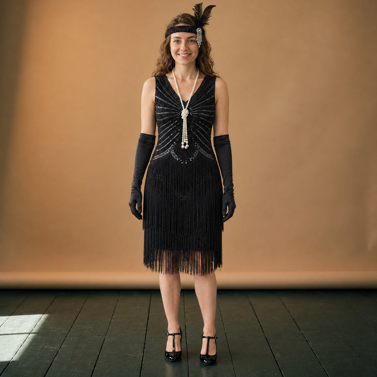Robe années 20 charleston noire à franges et paillettes portée en studio, vue en pied Bild
