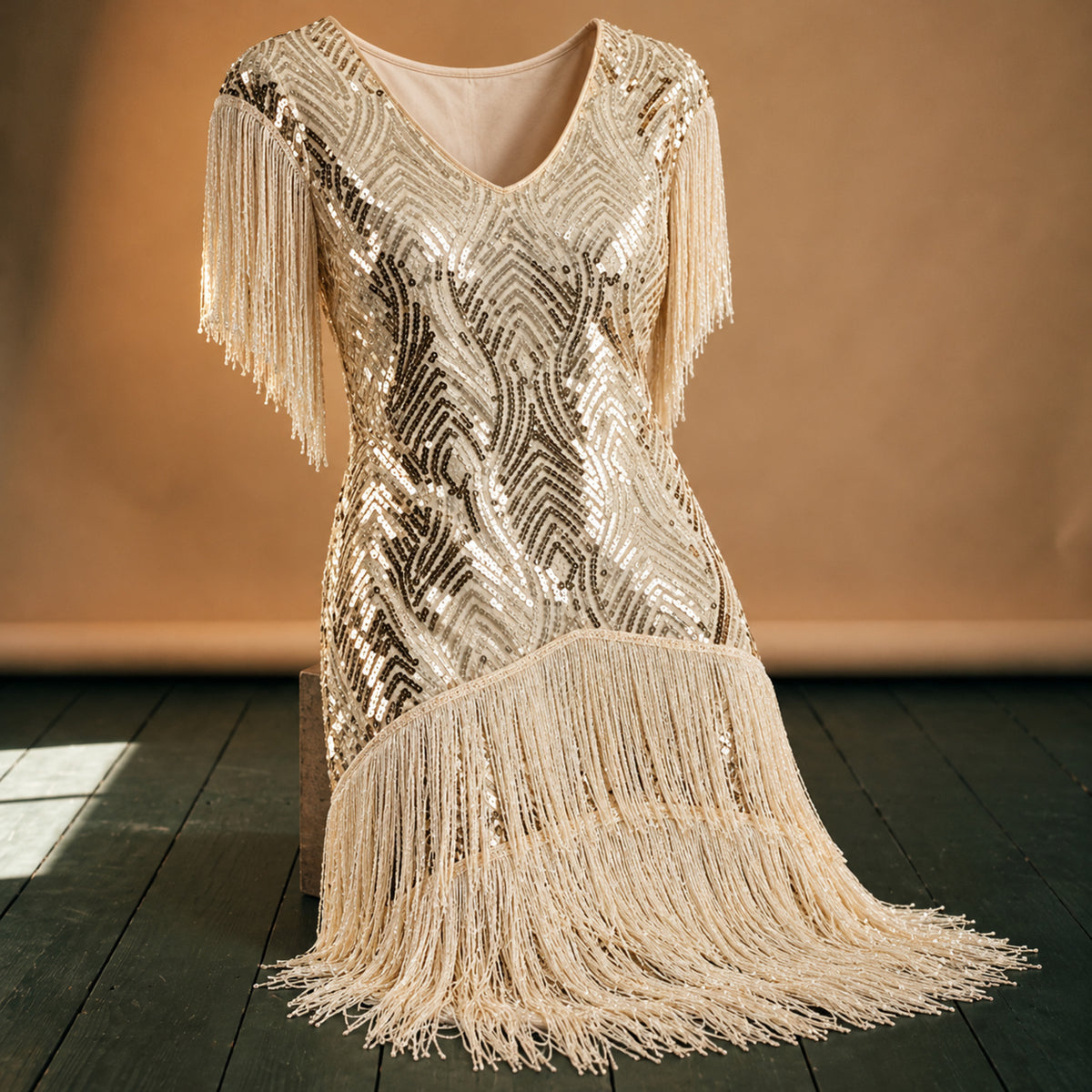 Gros plan sur les franges, les paillettes beiges et le sautoir de perles de la robe charleston beige Bild