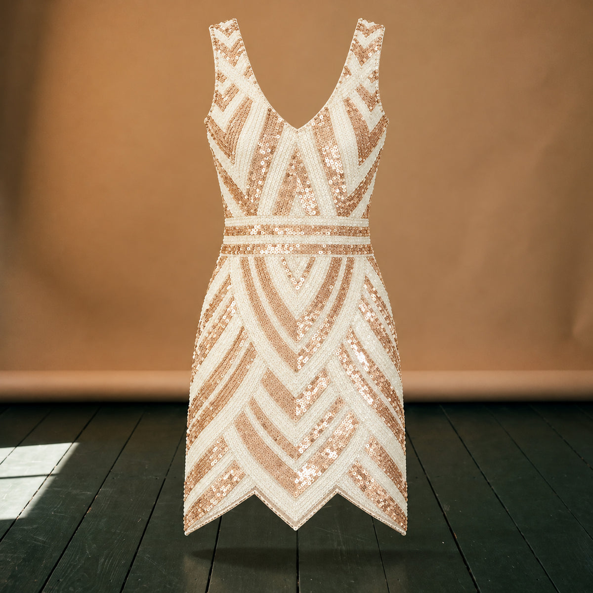 Gros plan sur les paillettes en chevrons ivoire et dorés et la maille de la robe charleston femme Bild