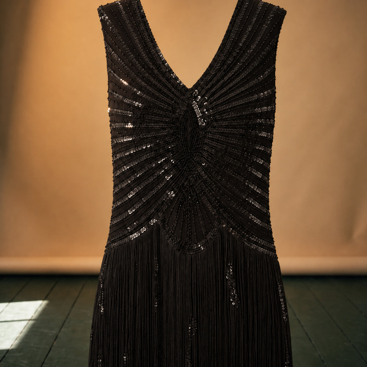 Gros plan sur les paillettes géométriques et les franges de la robe charleston Bild