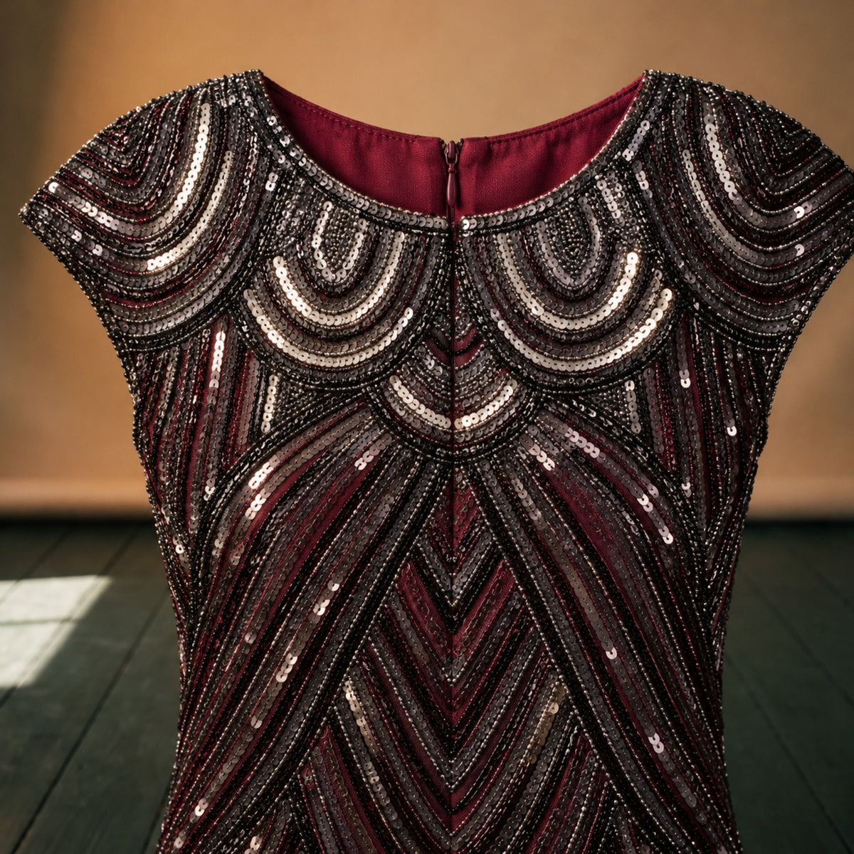 Gros plan sur les paillettes noires et argentées et les franges de la robe charleston rouge bordeaux Bild