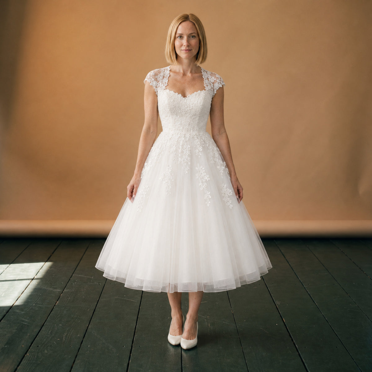 Robe de mariée courte en dentelle et tulle portée en studio, vue en pied de face Bild
