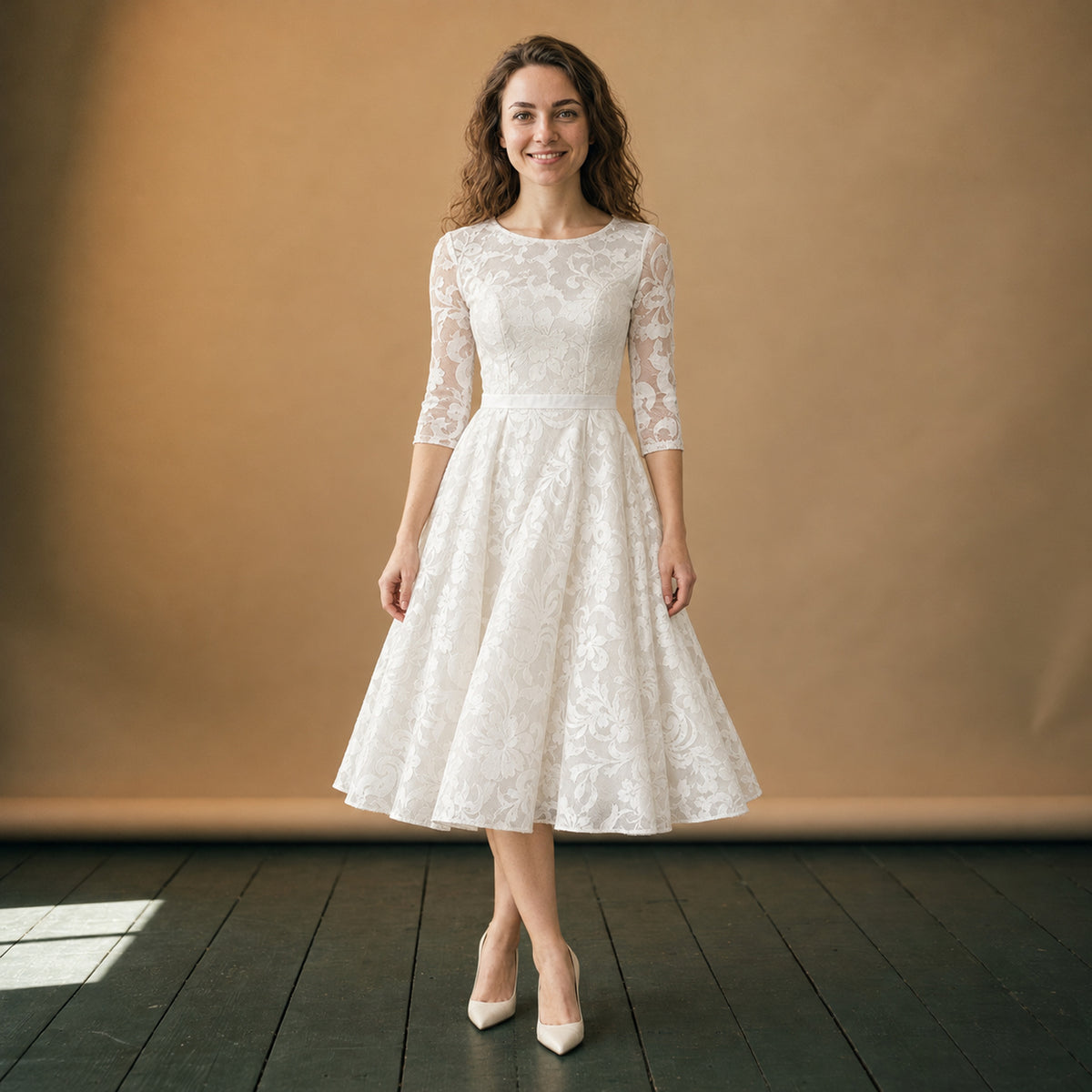 Robe de mariée mi-longue vintage en coton et dentelle portée en studio, manches trois-quarts, vue de face Bild