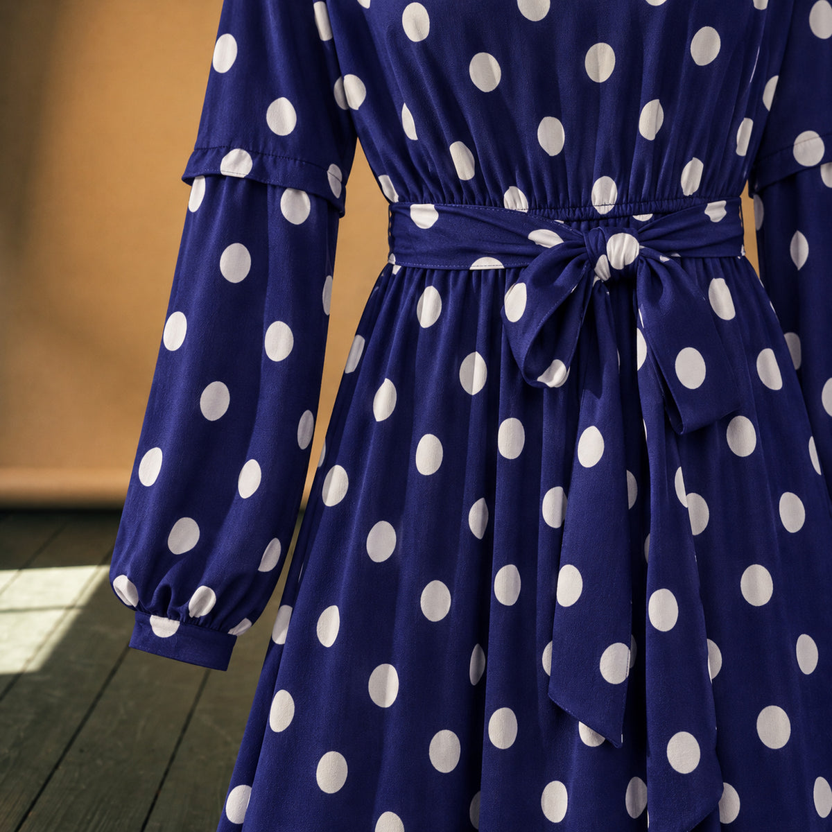 Gros plan sur les pois blancs, le polyester léger et la ceinture nouée de la robe maxi années 80 à pois bleus Bild
