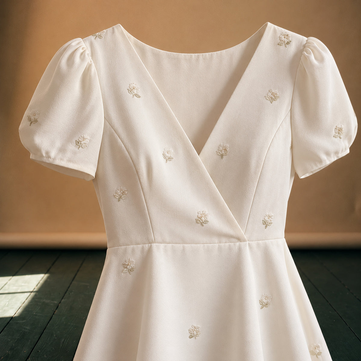 Gros plan sur les petites fleurs brodées et le tissu lisse de la robe style charleston pour mariage Bild