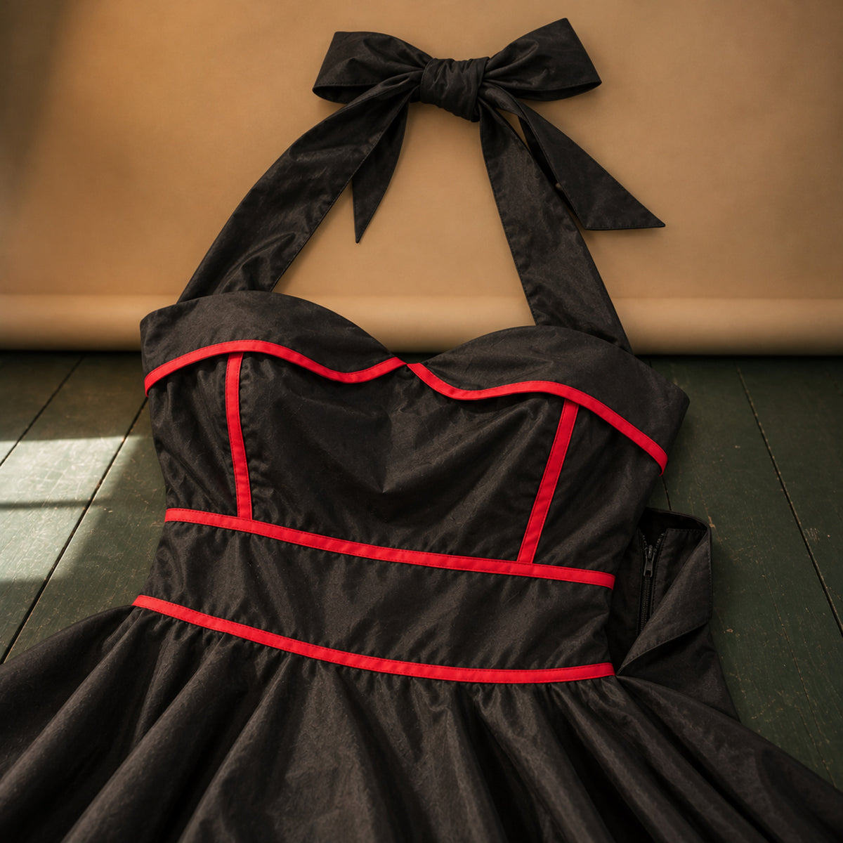 Gros plan sur le coton noir et le liseré rouge du buste de la robe vintage années 50 rockabilly Bild