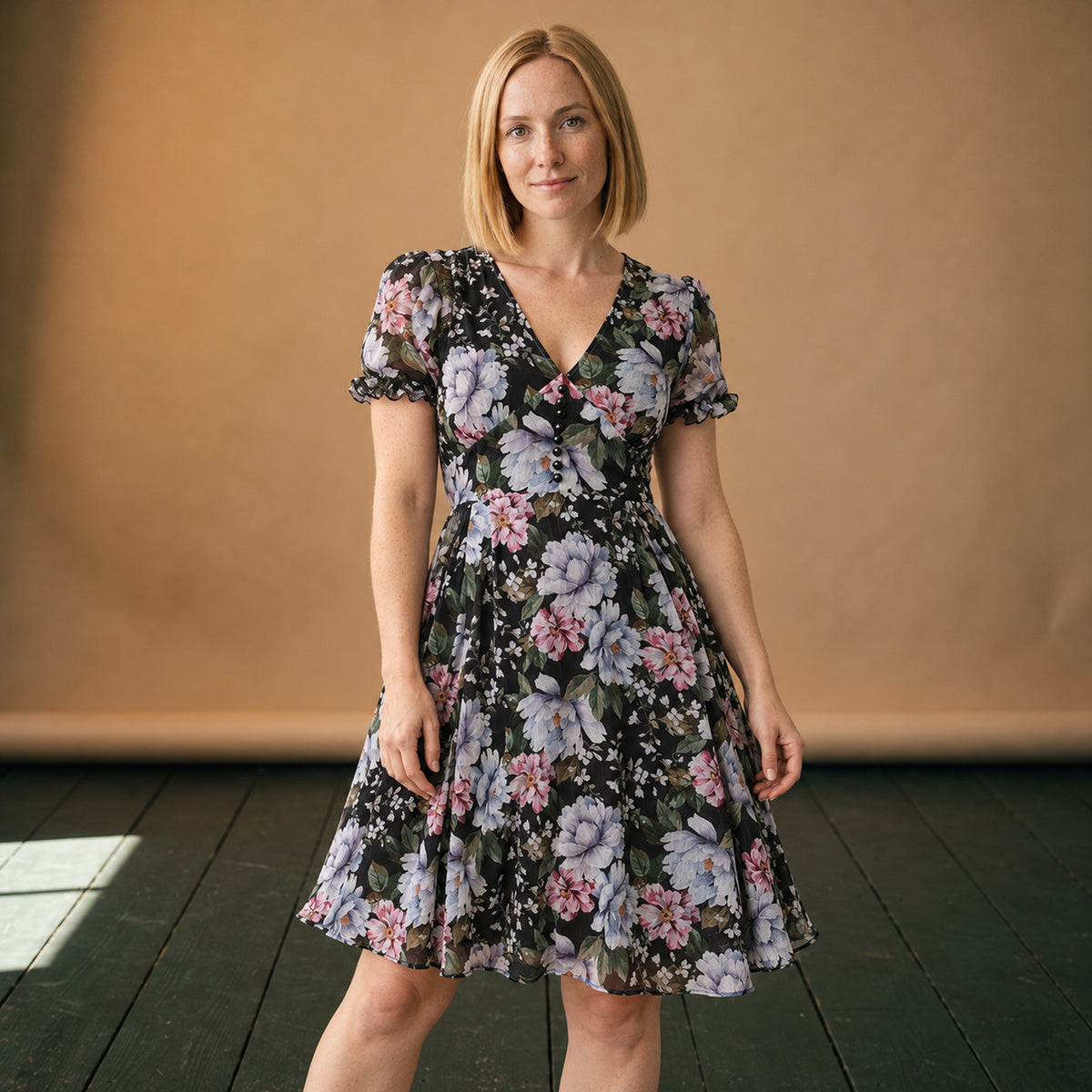 Robe vintage années 50 fleurie noire portée en studio, col V et jupe évasée, vue de face Bild