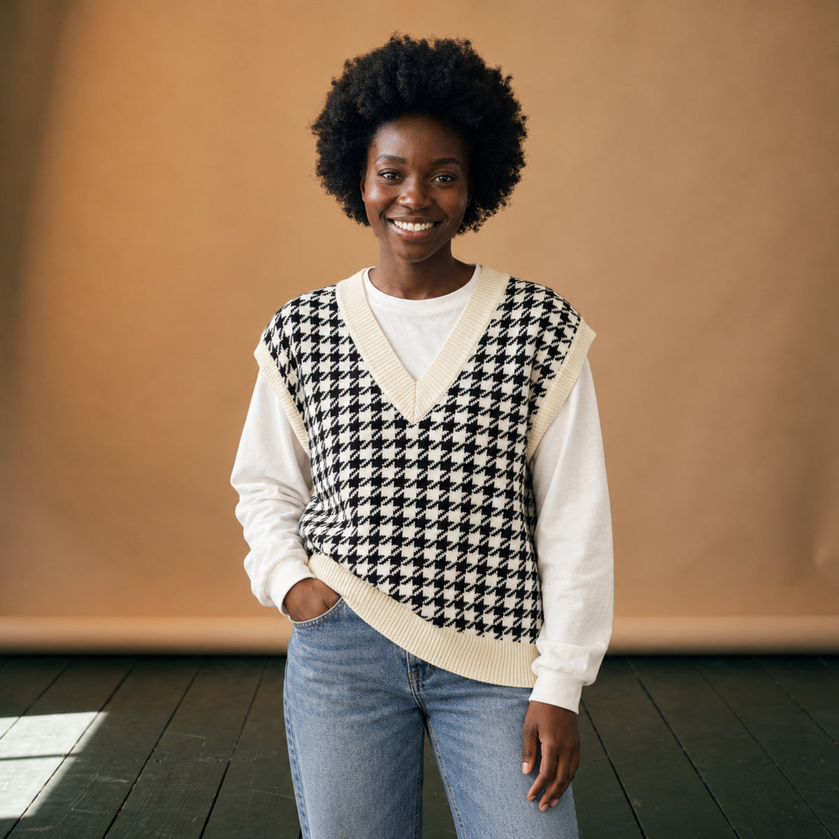 Sweat vintage femme sans manches en maille pied-de-poule noir et blanc porté sur une chemise blanche en studio Bild